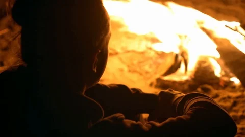 A man warms himself by the fire at night on the shore Stock Footage 115992464