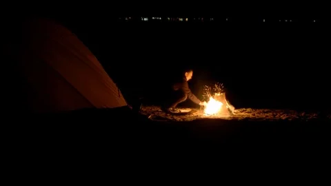 A man warms himself by the fire at night on the shore Stock Footage 115992555