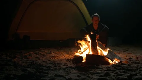 A man warms himself by the fire at night on the shore Stock Footage 115992970