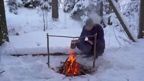 A man warms himself up by a fire in a winter forest Stockbeeldmateriaal 146605397