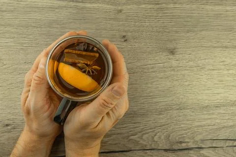 A man warms his cold hands with a clear double-walled glass filled with hot.. Stock Photos