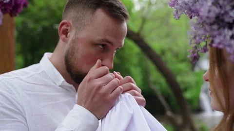 A man warms his girlfriend's hands by taking them in his. Woman in lilac wreath Stock Footage 205040420