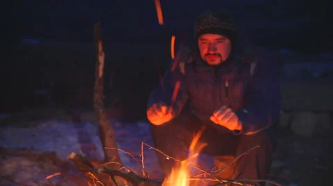 A man warms his hands by the fire in mountains Video stock 63366070