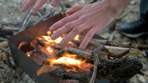 Man warms his hands by the fire Stock Footage 76499028
