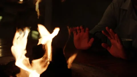 Man warms his hands in the flames of a fire. Stock Footage 273479583