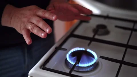 A man warms his hands over a burning fire. Natural gas burns on a stove Stock Footage 198827345