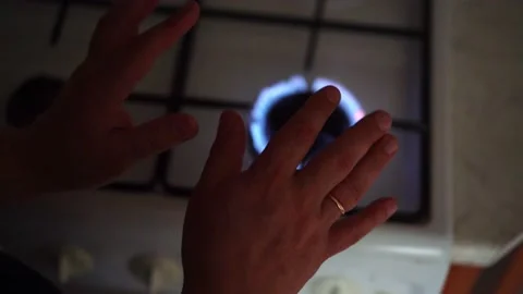 A man warms his hands over a burning fire. Natural gas burns on a stove Stock Footage 198827501