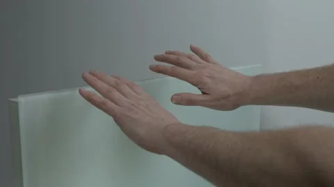 A man warms his hands over a wall-mounted electric heater. Additional heating Stock Footage 229254828