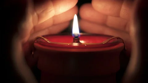 A man warms his palms from a burning candle on a black background. Video stock 220452162