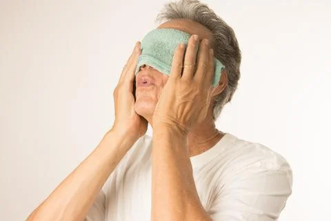 Man with a warn compress over his eyes for pain relief Stock Photos