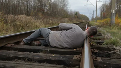 Man was about to commit suicide.Man lay his head on the railroad railroad tracks Stock Footage 143586245