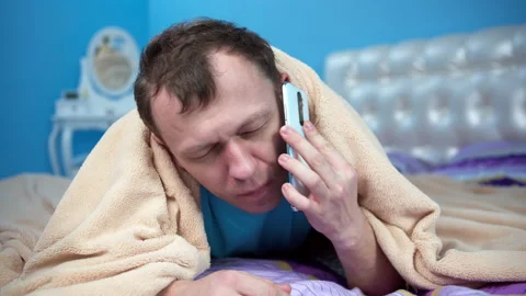 Man was sleeping under the covers taking cover with his head, woke up the phone Stock Footage 132394976