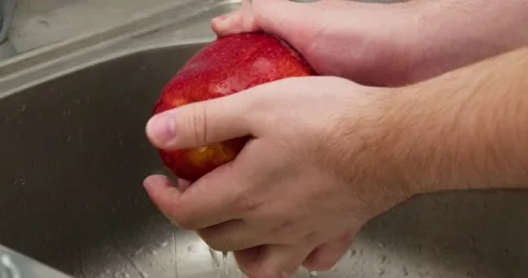 Man washes an apple Stock Footage 235512563