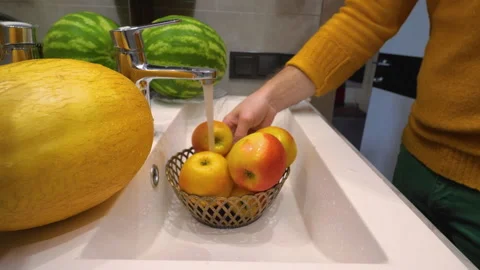 A man washes apples in a sink under a water tap.  Slow motion Stock Footage 293631376