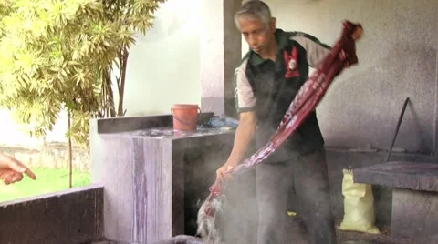 Man washes batik textile in hot water at the factory in Kandy, Sri Lanka. Stock Footage 63991649