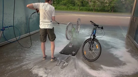 Man washes bike using pressure washers Stock Footage