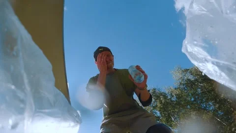 A man washes from a bottle, a guy washes with water from a bottle Stock Footage 248345943