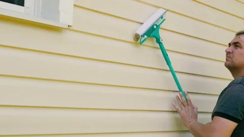 A man washes a building facade using a mop. Cleansing and maintenance service Stock Footage 202299961