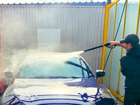 A man washes a car at a self-service car wash. Car wash concept Stock Photos
