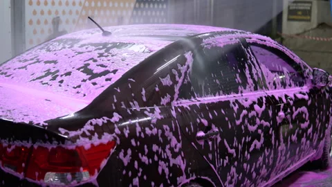 The man washes the car. Washes away pink foam with high pressure water Stock-Footage 136114053