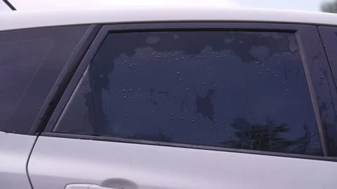 A man washes the car windows with a cloth before applying an anti-rain coating. Stockbeeldmateriaal 336914013