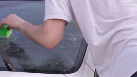 A man washes car windows with detergent before applying anti-rain Stock Footage 337323547