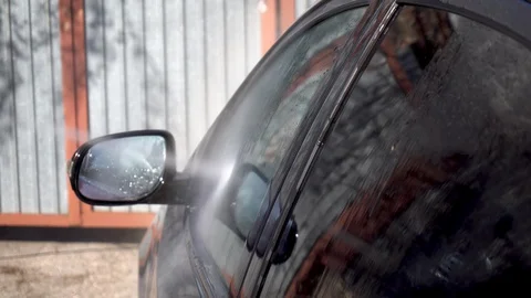 A man washes dirt off a car with a high-pressure water jet. Special detergent Stock Footage 129750791