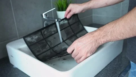 A man washes dirty air conditioning filter in the sink. Air conditioning service Stock Footage 130961608