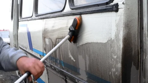 A man washes a dirty bus in the open air Stock Footage 108012331