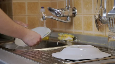 Man washes dirty dishes in kitchen Video stock 87305008