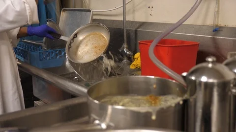 Man washes dishes in kitchen sprays with water scrubs with steel wool sanitiz Stockbeeldmateriaal 89374867