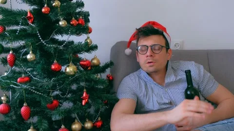 Man washes down antidepressants pills with wine from bottle near Christmas tree. Stock Footage 136521774