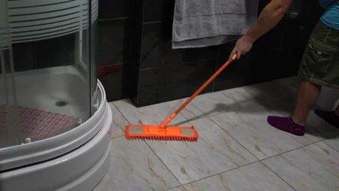 A man washes floor tiles with a mop in the bathroom Stock Footage 101584767