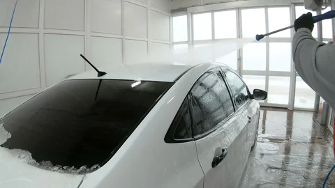 A man washes off the foam from the car Stock Footage 104281862