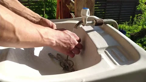 Man washes forks and spoons in the sink on the veranda of the house Stock Footage 133250256