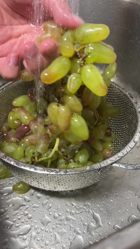 Man washes fresh ripe grape in colander in metal sink in kitchen under faucet Stock Footage 303781218