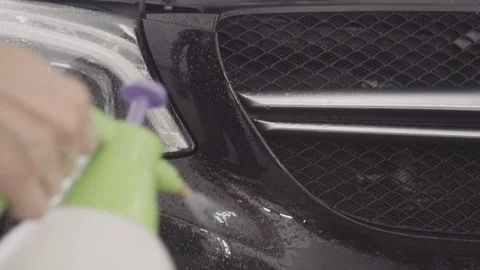 A man washes the front of the car before applying a protective layer on it Stock Footage 93602791