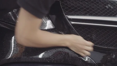 A man washes the front of the car before applying a protective layer on it Stock Footage 93602854