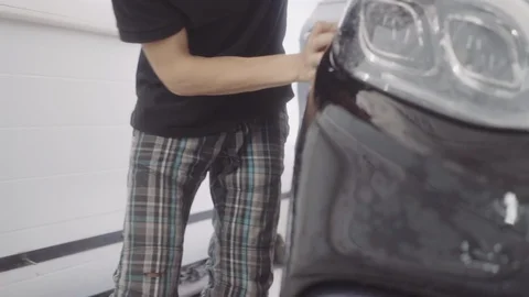 A man washes the front of the car before applying a protective layer on it Stock Footage 93602895