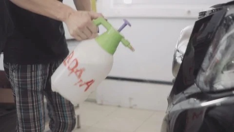 A man washes the front of the car before applying a protective layer on it Stock Footage 93602958