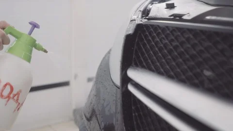 A man washes the front of the car before applying a protective layer on it Stock Footage 93602976
