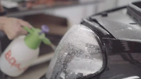 A man washes the front of the car before applying a protective layer on it Stock Footage 93603011