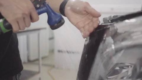 A man washes the front of the car before applying a protective layer on it Stock Footage 93603089