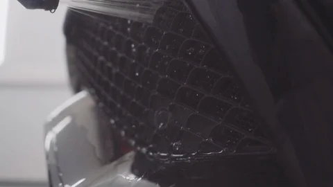 A man washes the front of the car before applying a protective layer on it Stock Footage 93603231