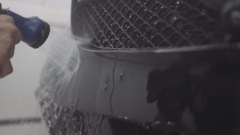 A man washes the front of the car before applying a protective layer on it Stock Footage 93603351