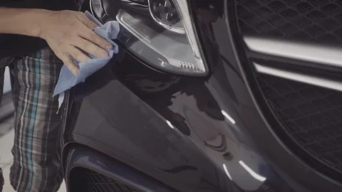 A man washes the front of the car before applying a protective layer on it Stock Footage 93603516