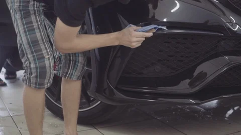 A man washes the front of the car before applying a protective layer on it Stock Footage 93603651