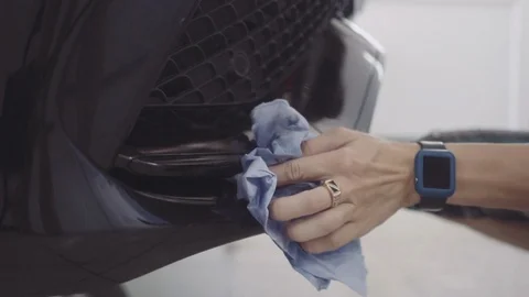 A man washes the front of the car before applying a protective layer on it Stock Footage 93603738