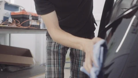 A man washes the front of the car before applying a protective layer on it Stock Footage 93603873