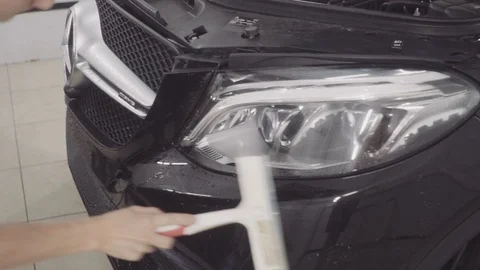 A man washes the front of the car before applying a protective layer on it Stock Footage 93603919